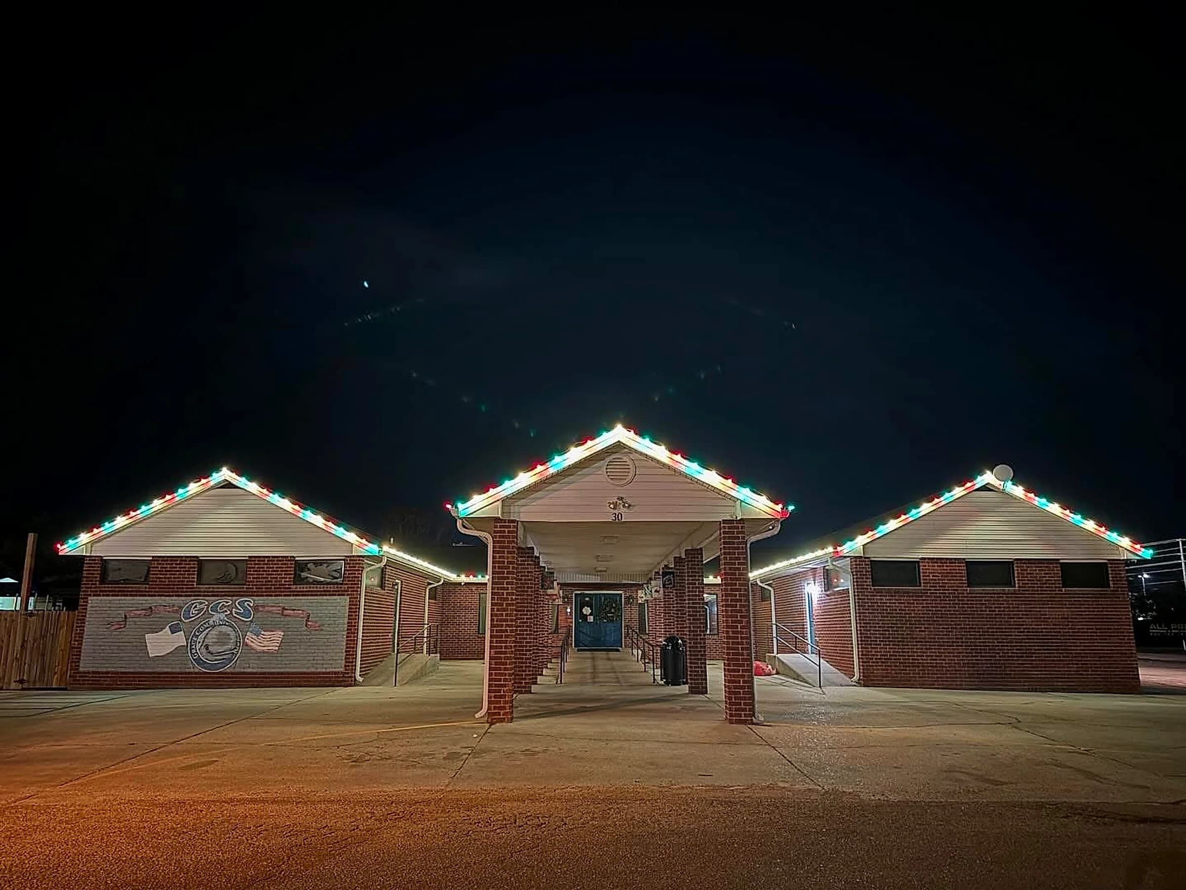 Southeast Lights display at Grace Community School in Hattiesburg: three gables and the covered entry walkway outlined in alternating red, green and warm white C9 bulbs