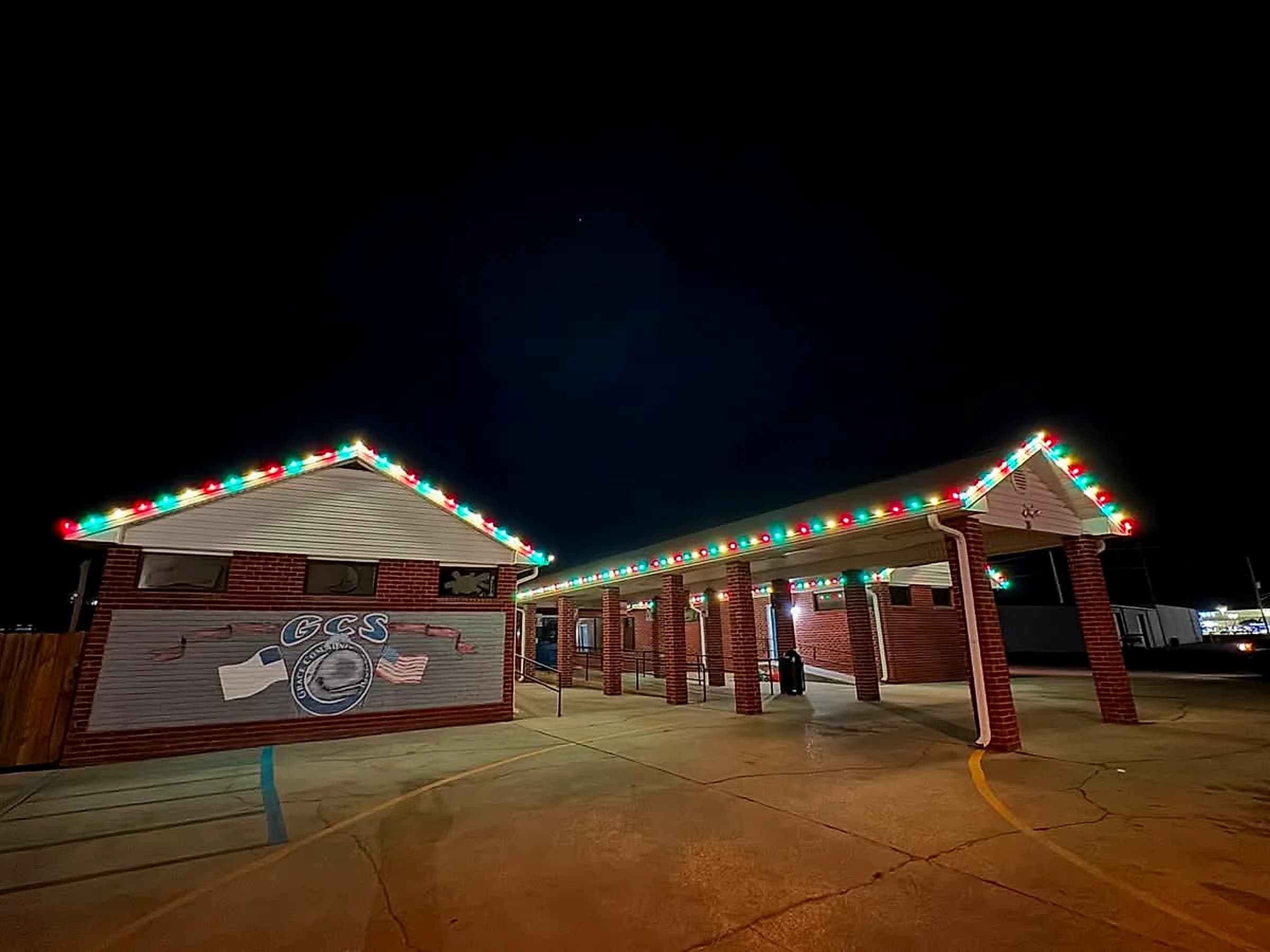 The Grace Community School mural elevation at night with red, green and warm white C9 along the gable rake and the walkway roof beyond it