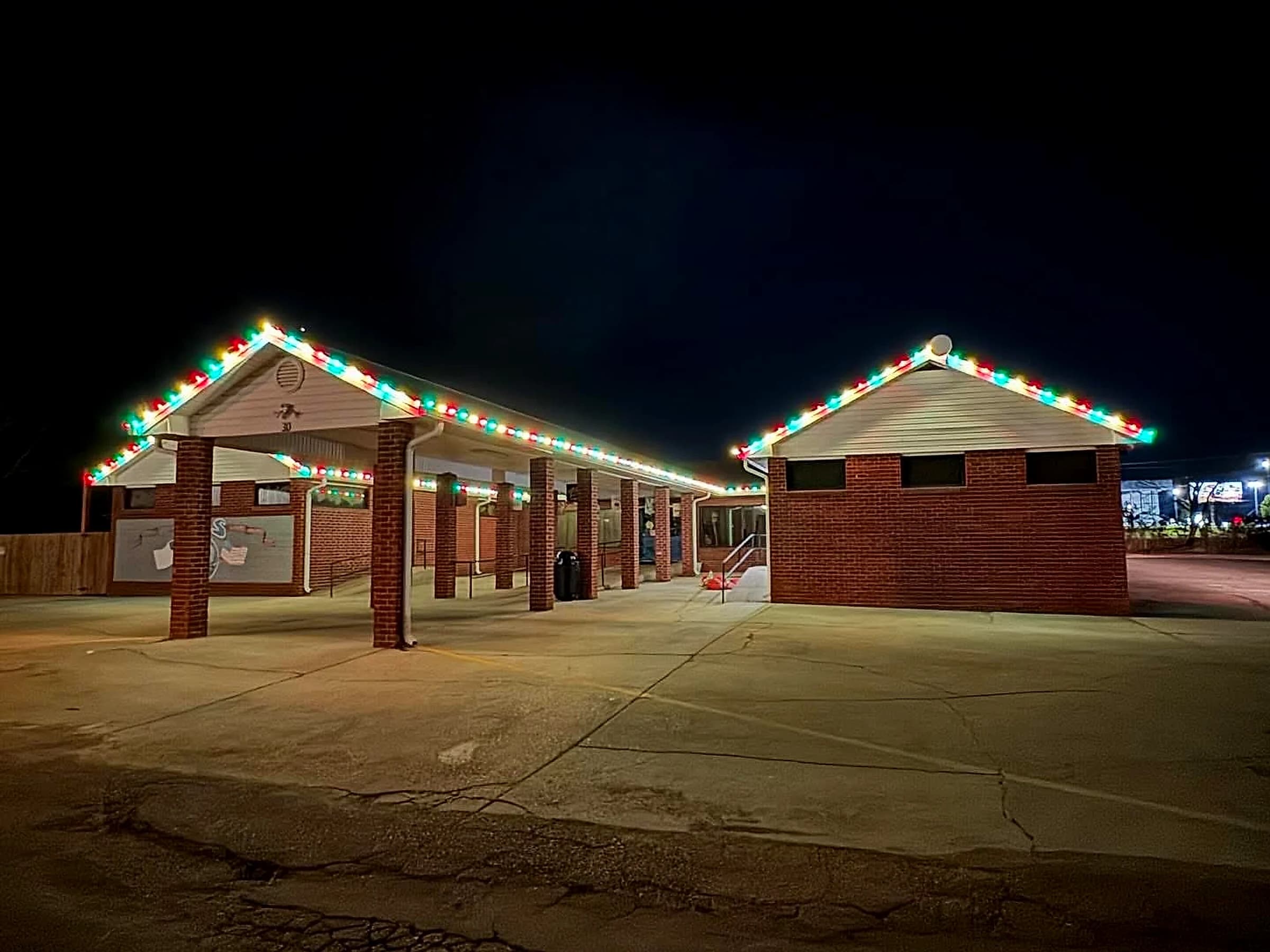 Grace Community School at night from the parking lot, red, green and warm white C9 running the full length of the covered walkway fascia and up each gable rake