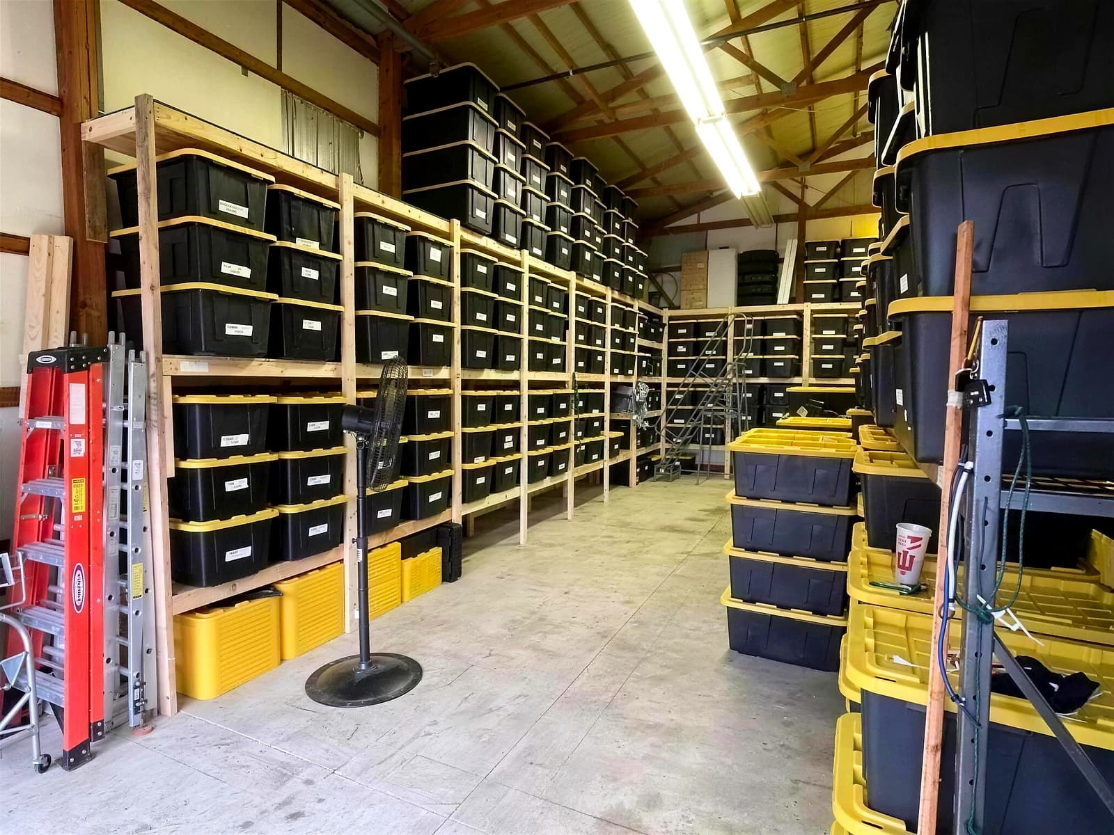 Organized warehouse shelving with labeled bins and neatly coiled light strands ready for next season