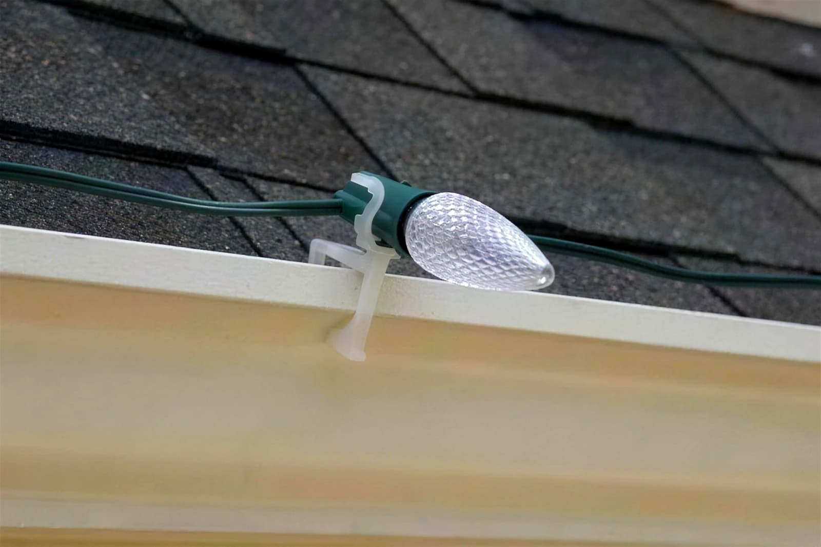Close-up of commercial-grade C9 bulbs clipped along a roof edge, warm filaments glowing